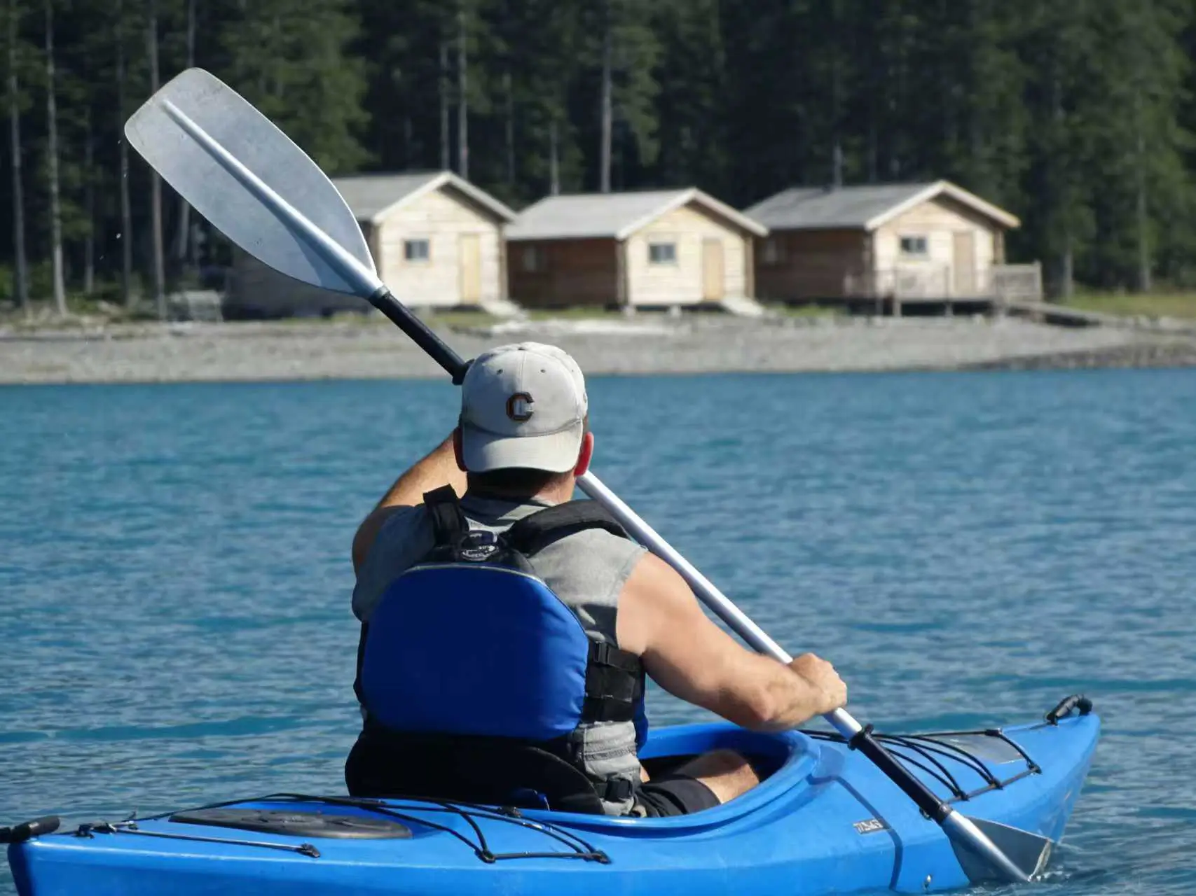 A kayaker paddling on a calm lake surrounded by nature, illustrating the need for quiet and lightweight propulsion.