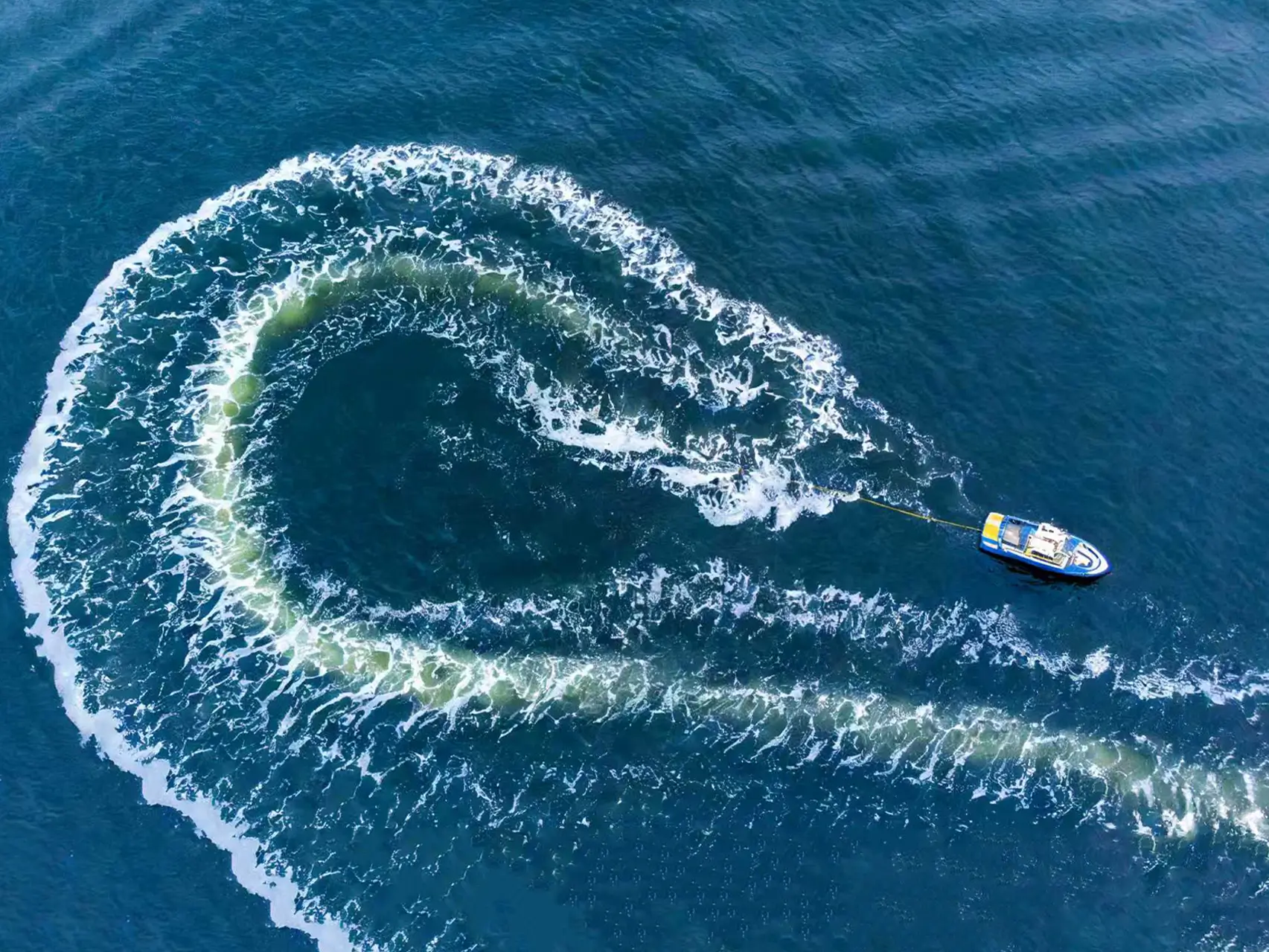 Aerial view of a boat making a sharp turn and creating a wake, representing high-performance outboard motor capabilities.