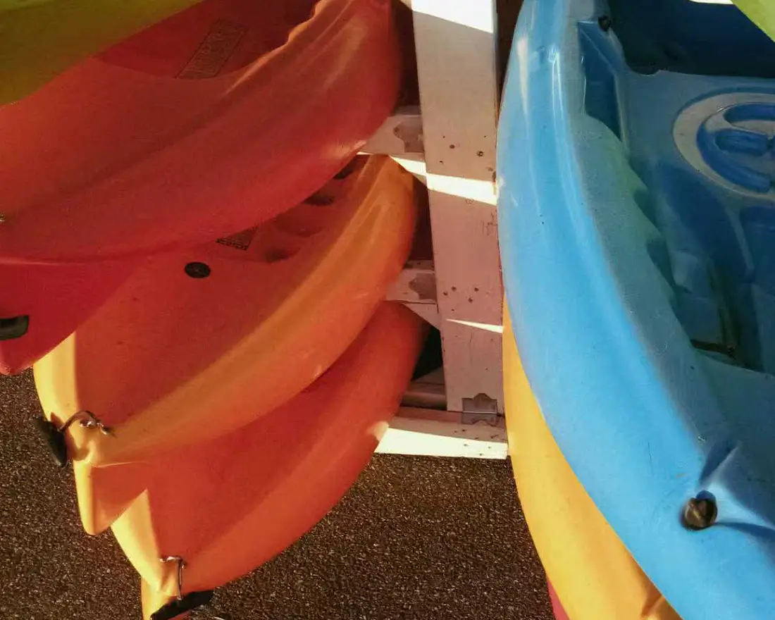 Multiple kayaks stored together, illustrating the need for adaptable and non-permanent motor mounting systems